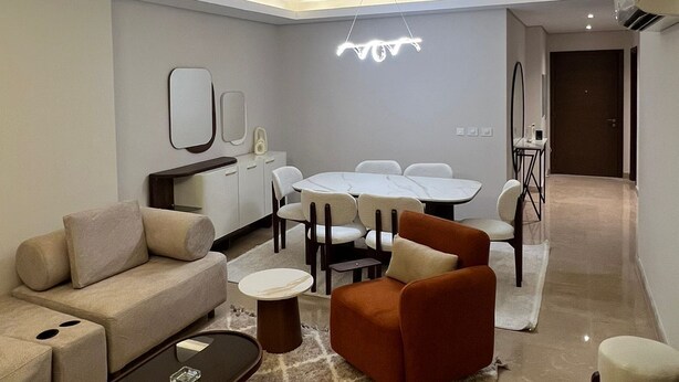 A modern living room with a sofa, coffee table, and a dining area with a table and chairs. - Spacious 3-bedroom apartment in charming Giza Governorate with AC (Giza Governorate)