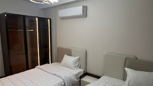 A bedroom with two beds, a wardrobe, an air conditioning unit, and a modern ceiling light fixture. - Spacious 3-bedroom apartment in charming Giza Governorate with AC (Giza Governorate)