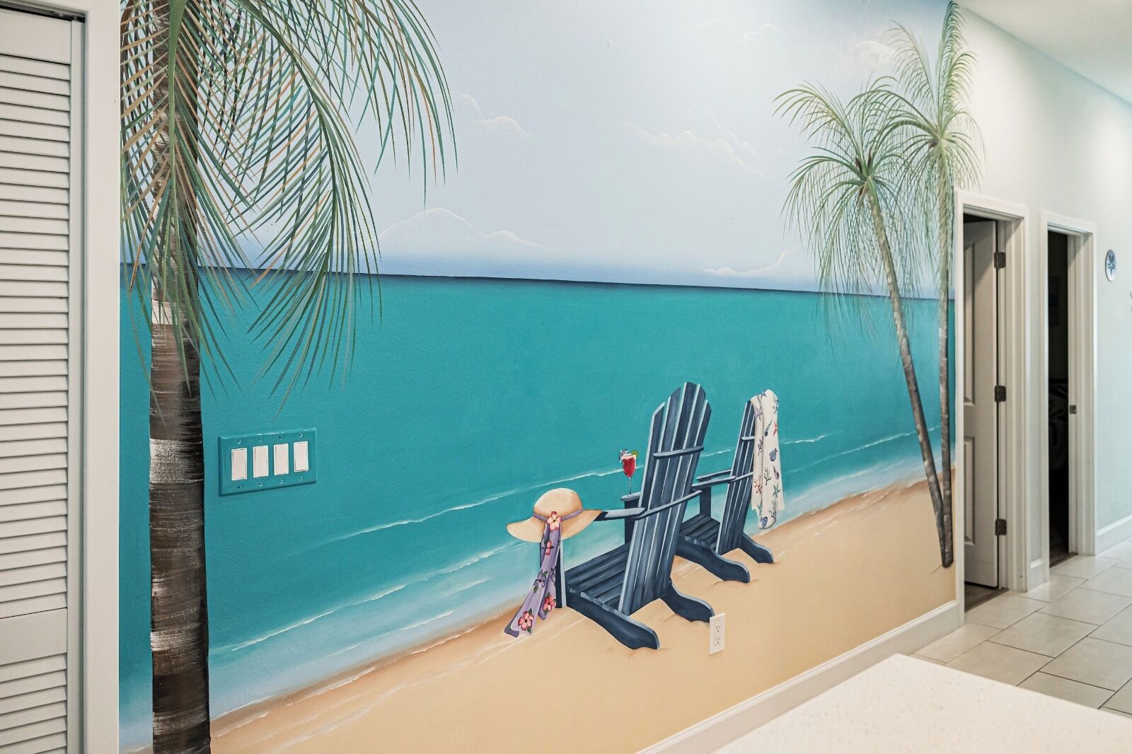 A beach-themed mural with a chair, a drink, and a hat.