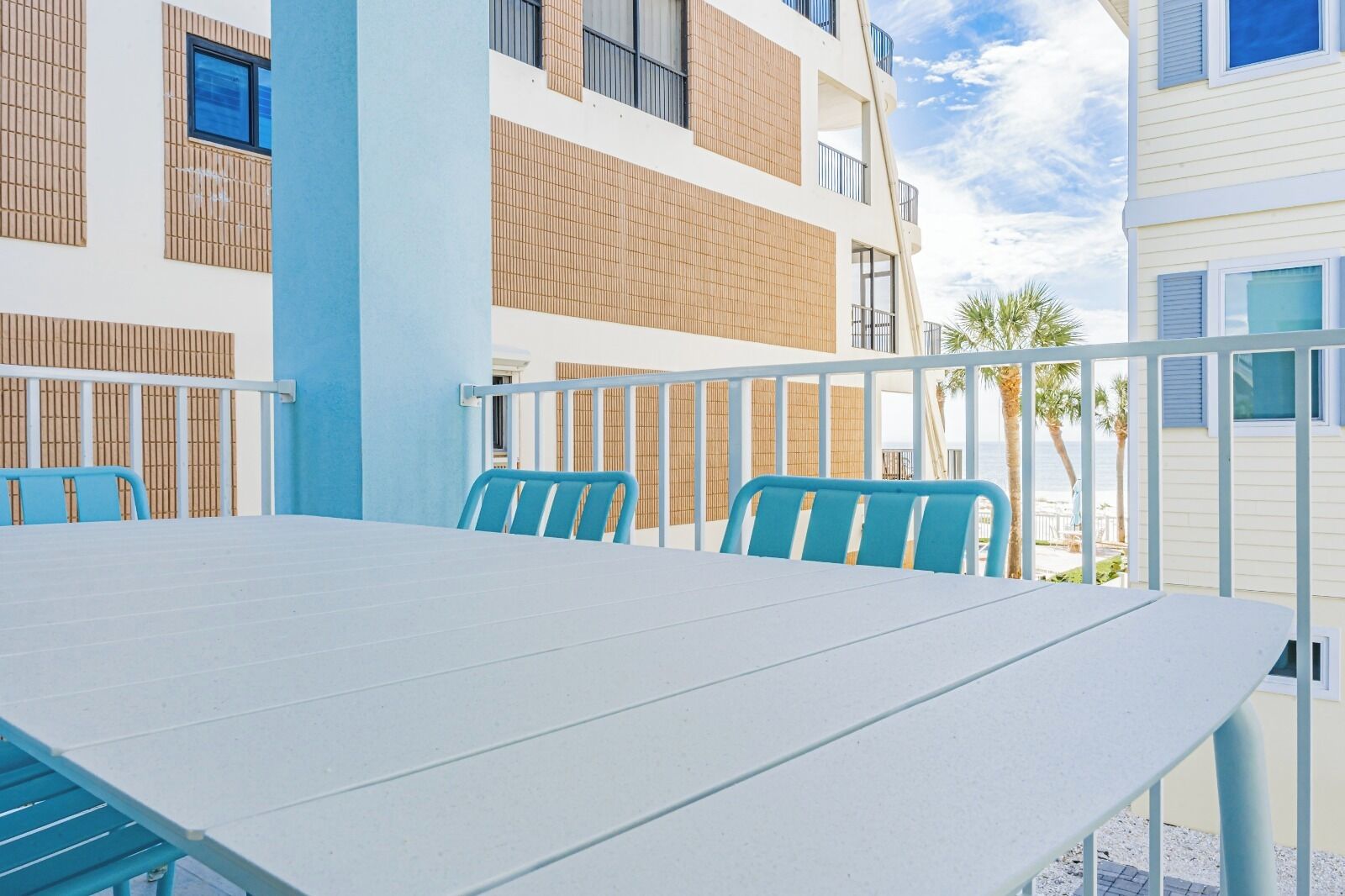 Un balcon avec une table et des chaises, donnant sur une plage.