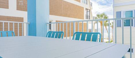 Un balcon avec une table et des chaises, donnant sur une plage.