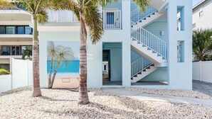Um edifício moderno com fachada azul clara, uma escadaria e vista para a praia.