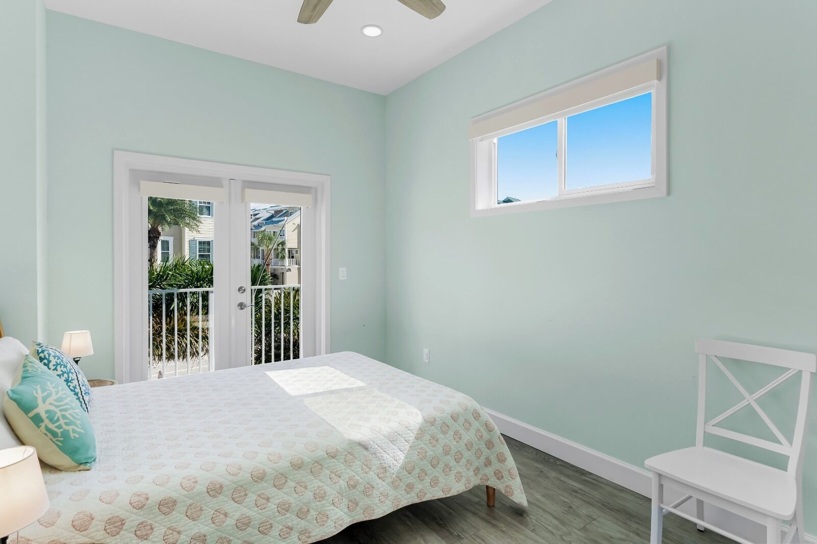 Une chambre à coucher comprenant un lit, une chaise, une fenêtre et une porte donnant sur un balcon.
