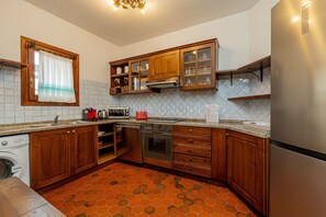 Eine Küche mit Holzausstattung, Backofen, Mikrowelle und einem Edelstahlkühlschrank.