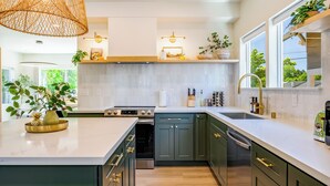 A modern kitchen with a large island, built-in appliances, and a window overlooking greenery. - AC / New Remodel / Chef's Kitchen / BBQ / Cap Hill (Seattle)