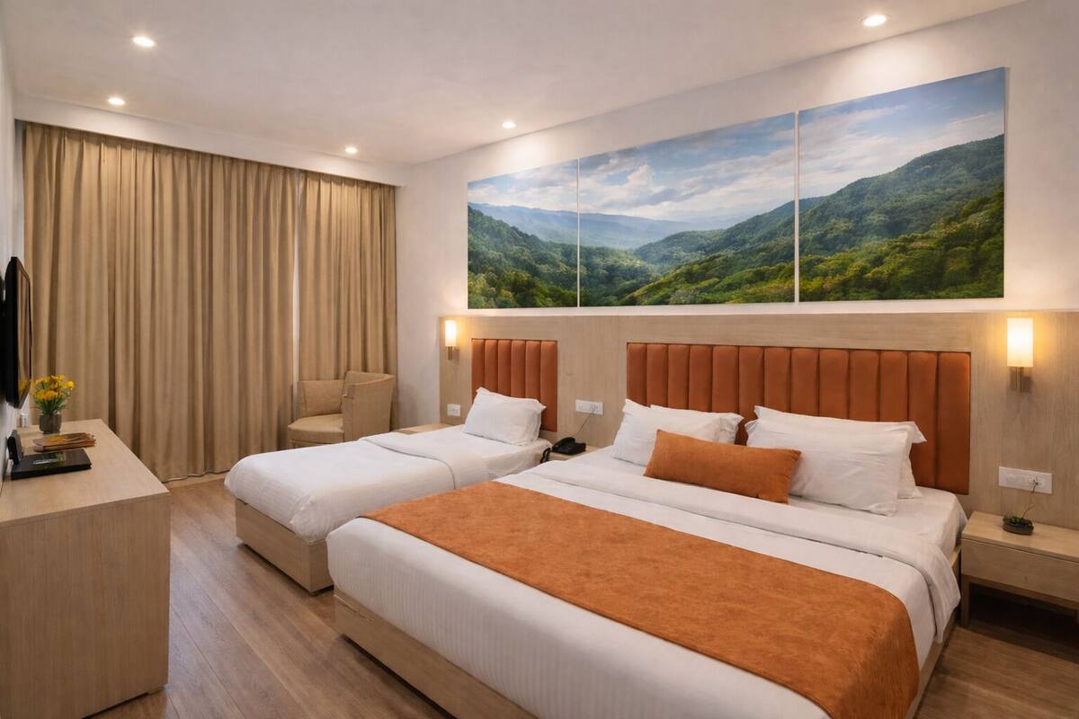 Ett hotellrum med två sängar, ett skrivbord, en stol, en tavla som föreställer ett landskap och en tv.