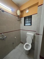 A small, tiled bathroom with a toilet, a shower, and a window.