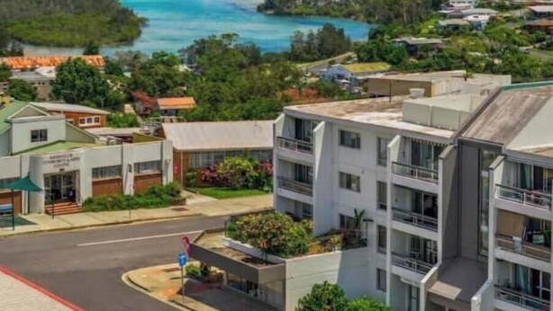 A residential area with modern buildings, a road, and a river. - Coastal Calm - Stylish Escape in Heart of Nambucca (Nambucca Heads)