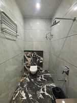 A bathroom with a toilet, shower, and a towel rack.