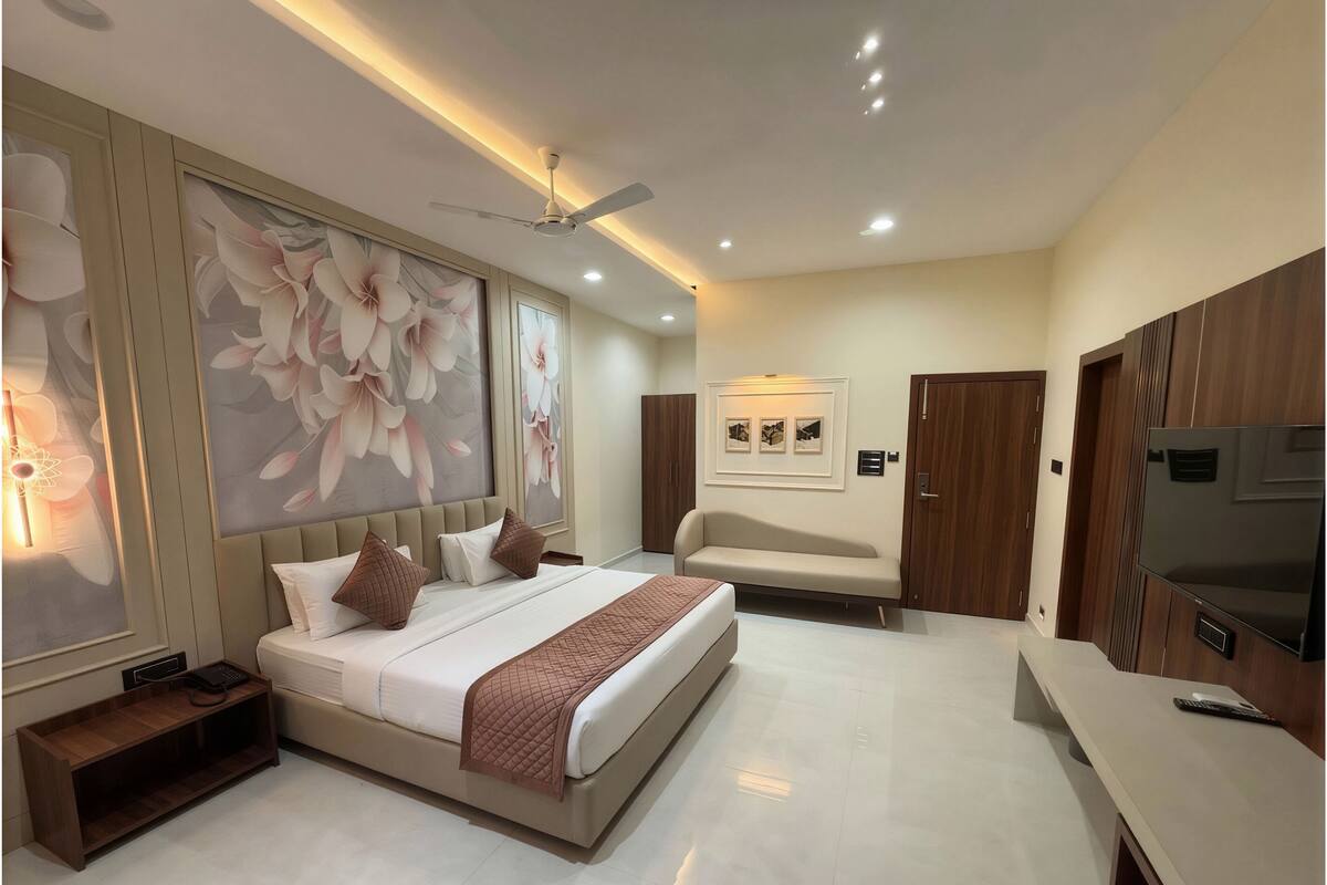 Un dormitorio moderno con cama, sofá, televisor y obras de arte en las paredes.