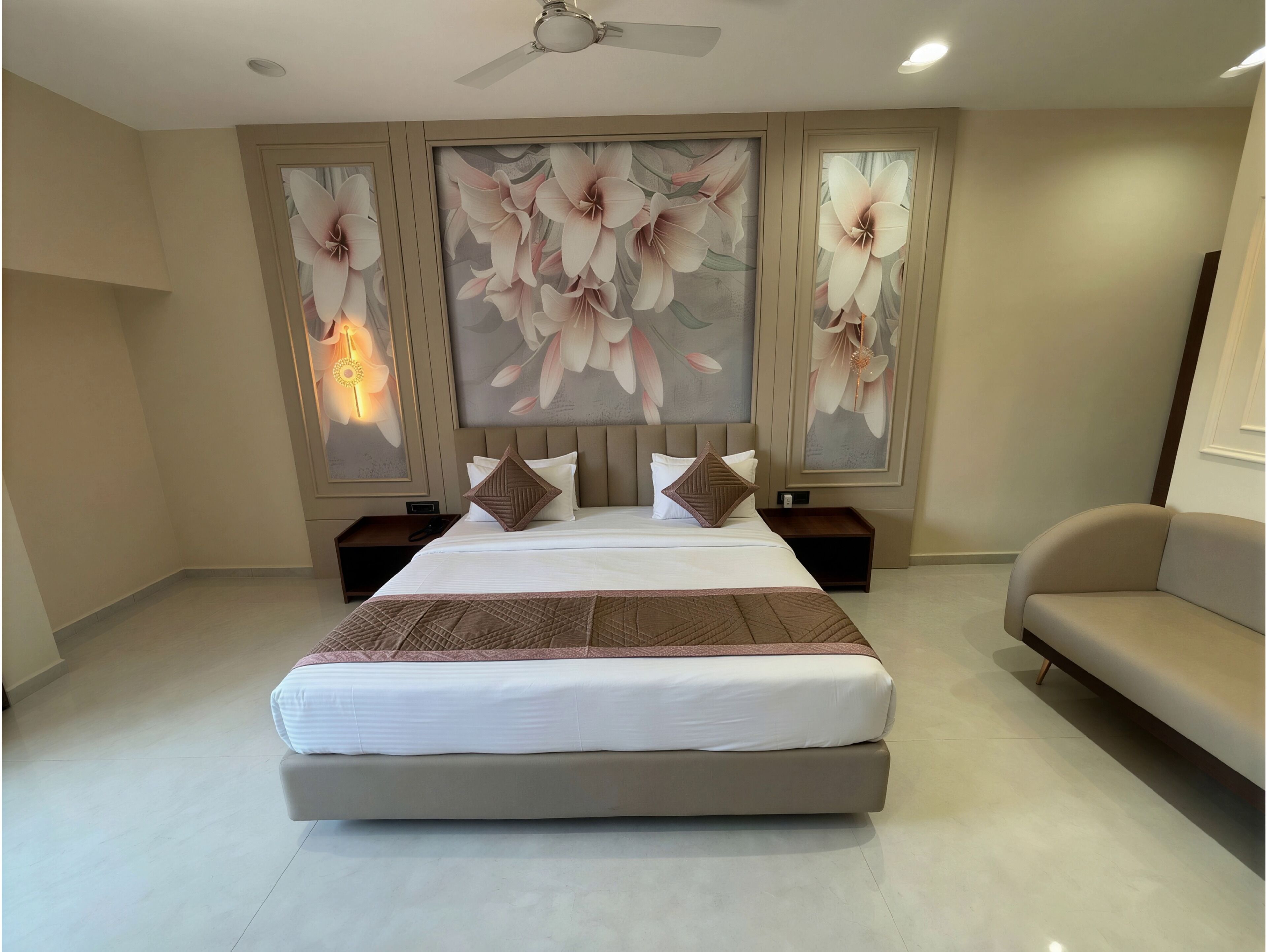 A bedroom with a large bed, a ceiling fan, and floral wall art.