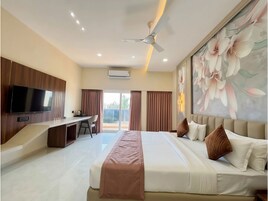 A hotel room with a bed, a desk, a television, and a ceiling fan.