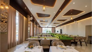 A dining area with multiple tables, each set with plates, cutlery, and glasses. - Shree Agrawal Avenue (Ujjain)