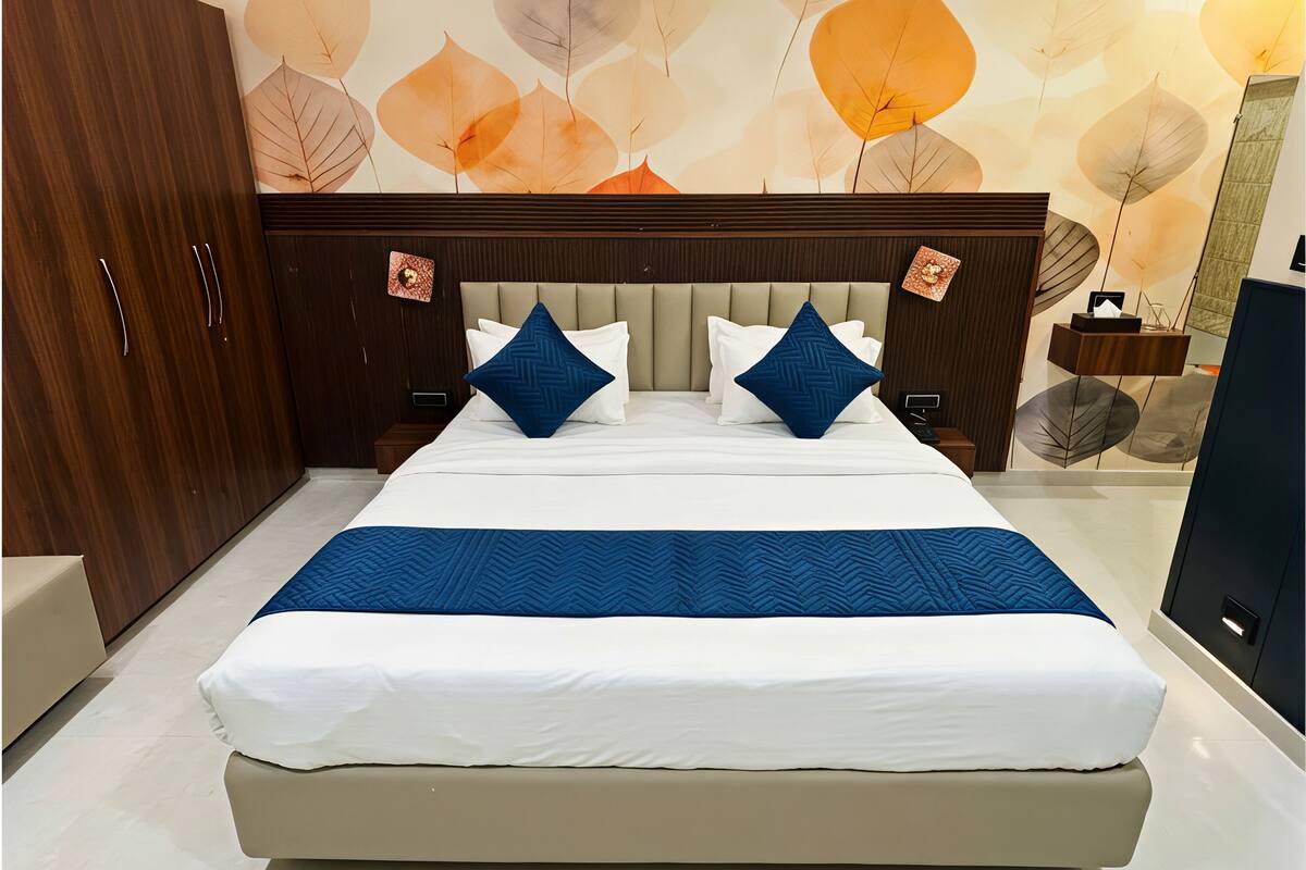 Un dormitorio con una cama, armario de madera y una pared con motivos de hojas.