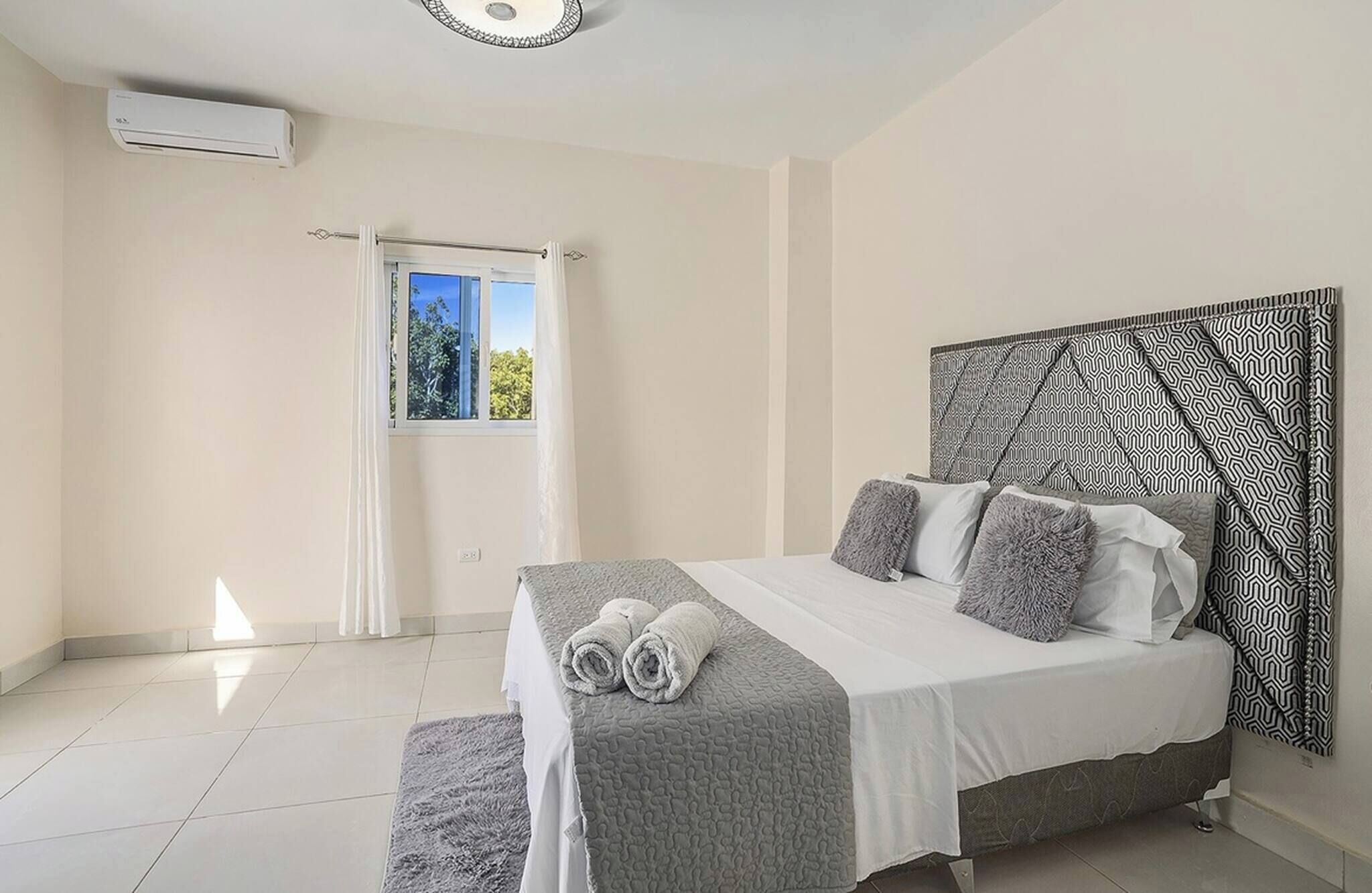 A bedroom with a bed, a window, and an air conditioning unit.