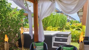Un patio al aire libre con mobiliario de mimbre, una mesa y una parrilla.