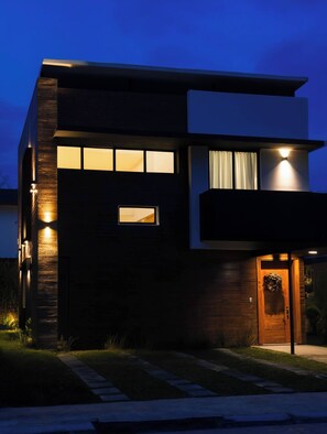 A modern two-story house with a well-lit entrance, a visible window, and a pathway leading to the door. - Villa with jacuzzi and terrace · Ideal Easter (Punta Cana)