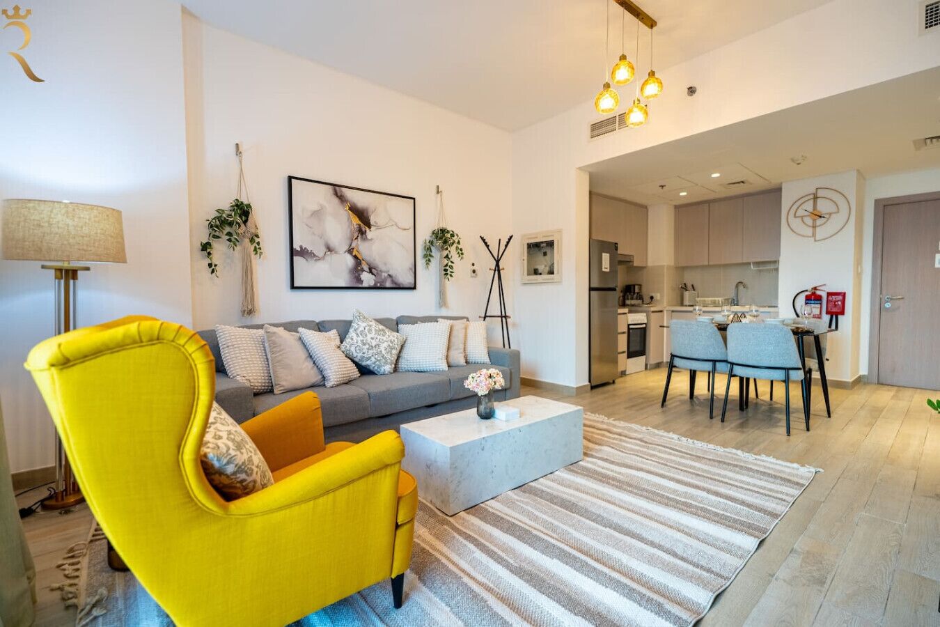 Een moderne woonkamer met een bank, een gele fauteuil, een salontafel en een eethoek met stoelen.
