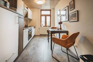 A compact kitchen with a dining area, a window, and framed pictures on the wall.