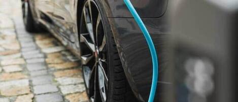 A parked electric car with a charging cable connected to it.