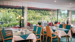 A restaurant with tables set for dining, chairs, and potted plants. - Hotel Bisenius (Traben-Trarbach)