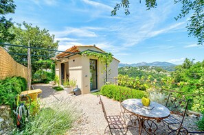 Una casa pequeña con un patio, una mesa con sillas y vistas al campo.