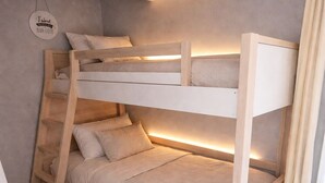 Una cama litera con escalera, una lámpara colgante y un letrero en la pared.