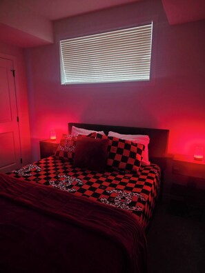Une chambre à coucher avec une couvre-lit à carreaux, une fenêtre avec des stores et des lampes de chevet.