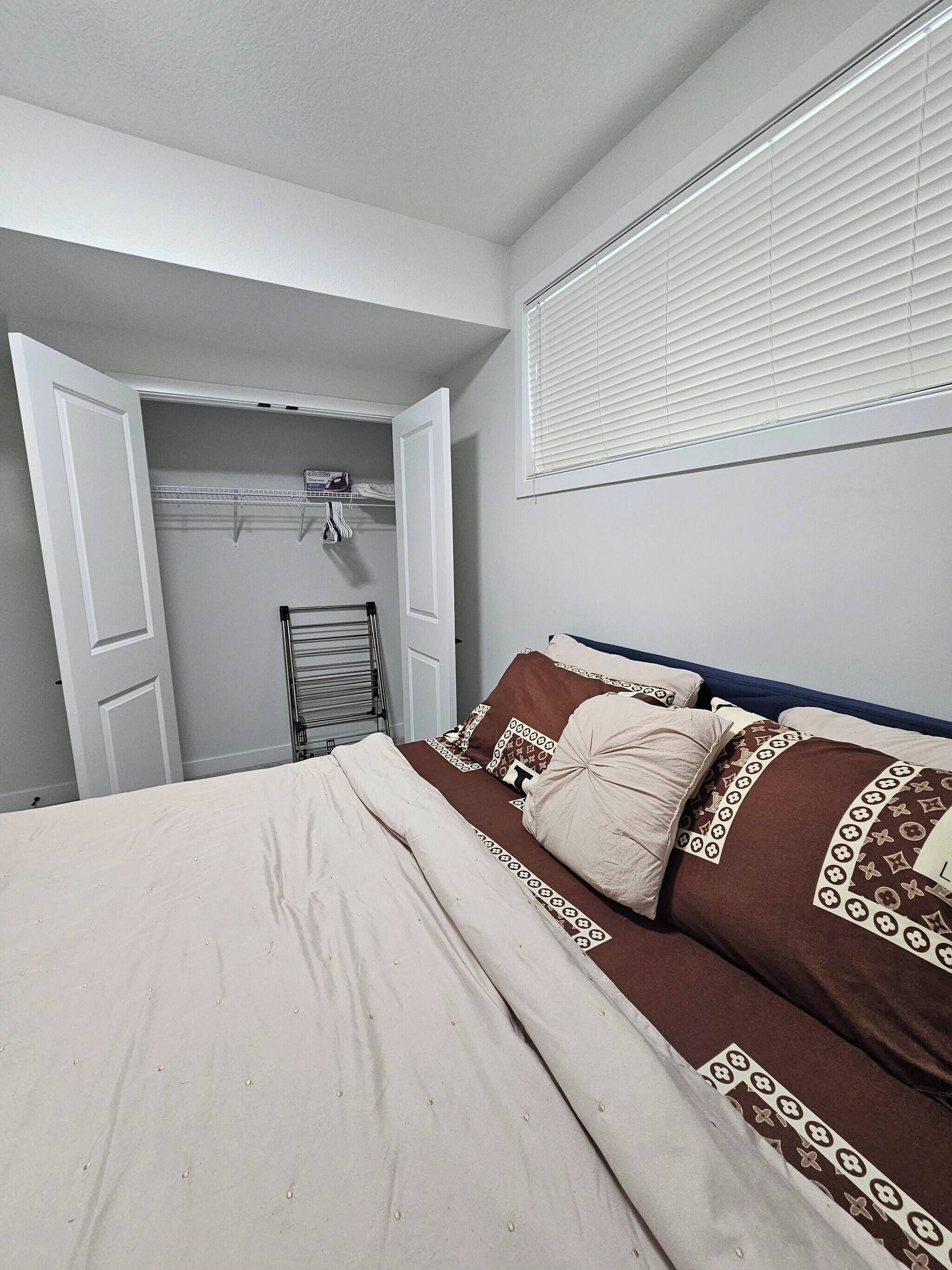 Ein Schlafzimmer mit einem Bett, einem Kleiderschrank, einem Handtuchhalter und einem Fenster mit Jalousien.