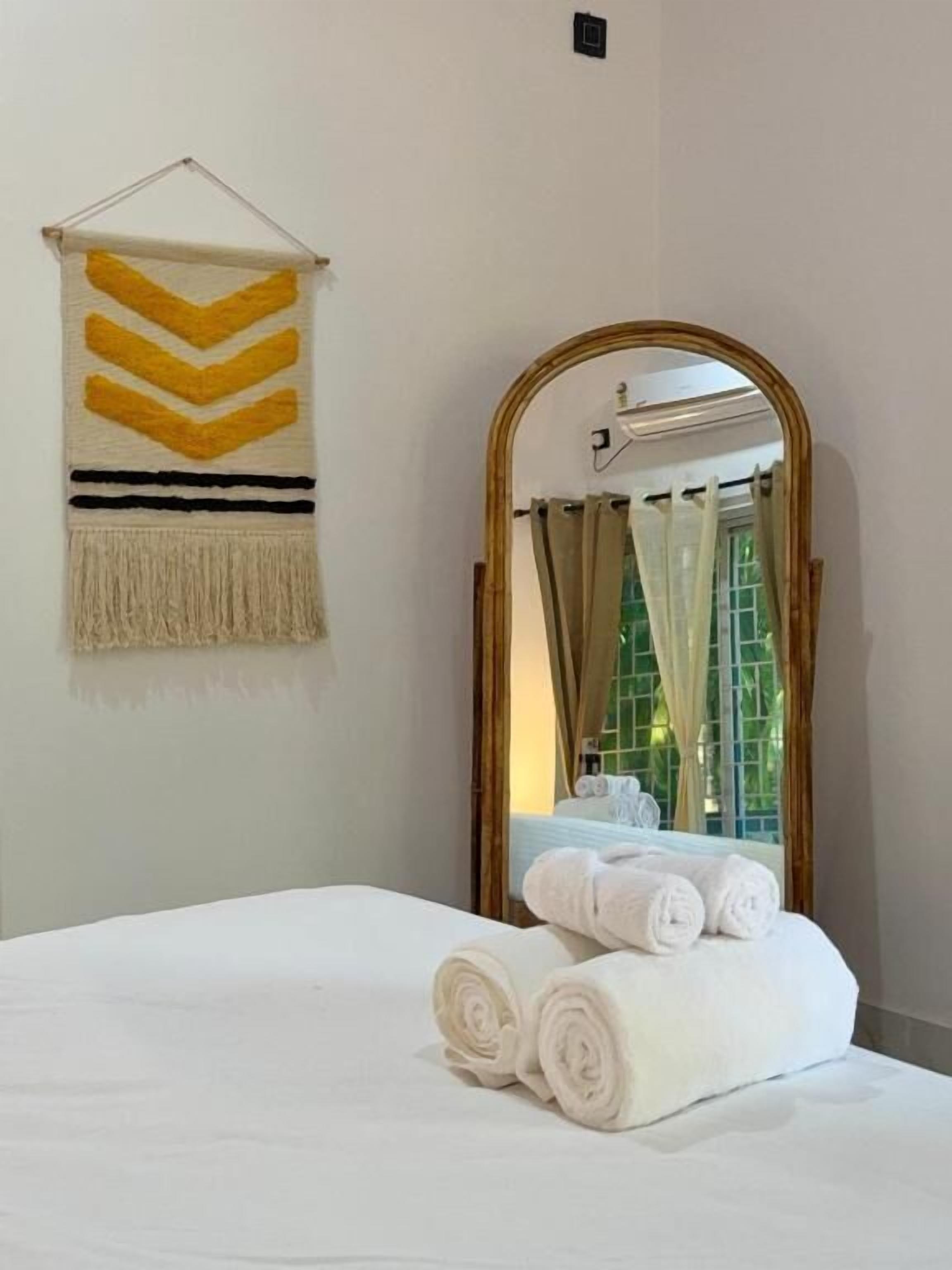 Ein Hotelzimmer mit Bett, Spiegel, Fenster mit Vorhängen und Wandbild.