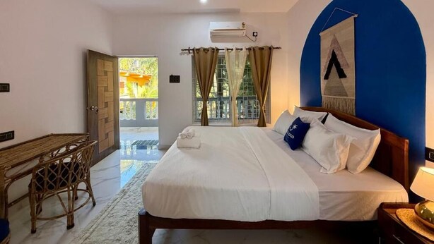 A bedroom with a bed, a desk, a chair, a ceiling fan, and an air conditioning unit. - Salt & Coco (Ashvem)