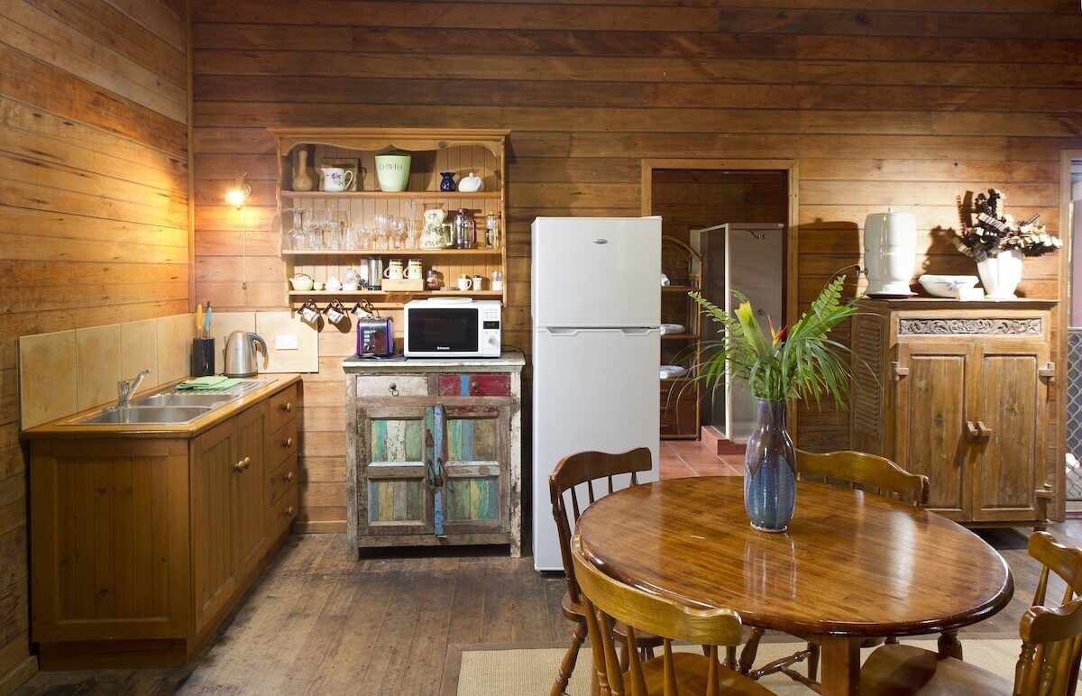 Un interior de madera con cocina equipada con refrigerador, microondas y armarios de madera.
