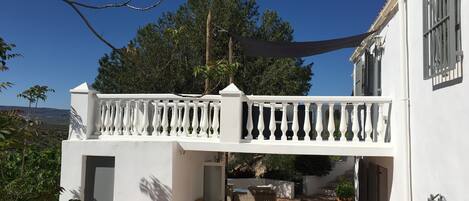 Un edificio blanco con balcón, mobiliario exterior y una fuente decorativa.