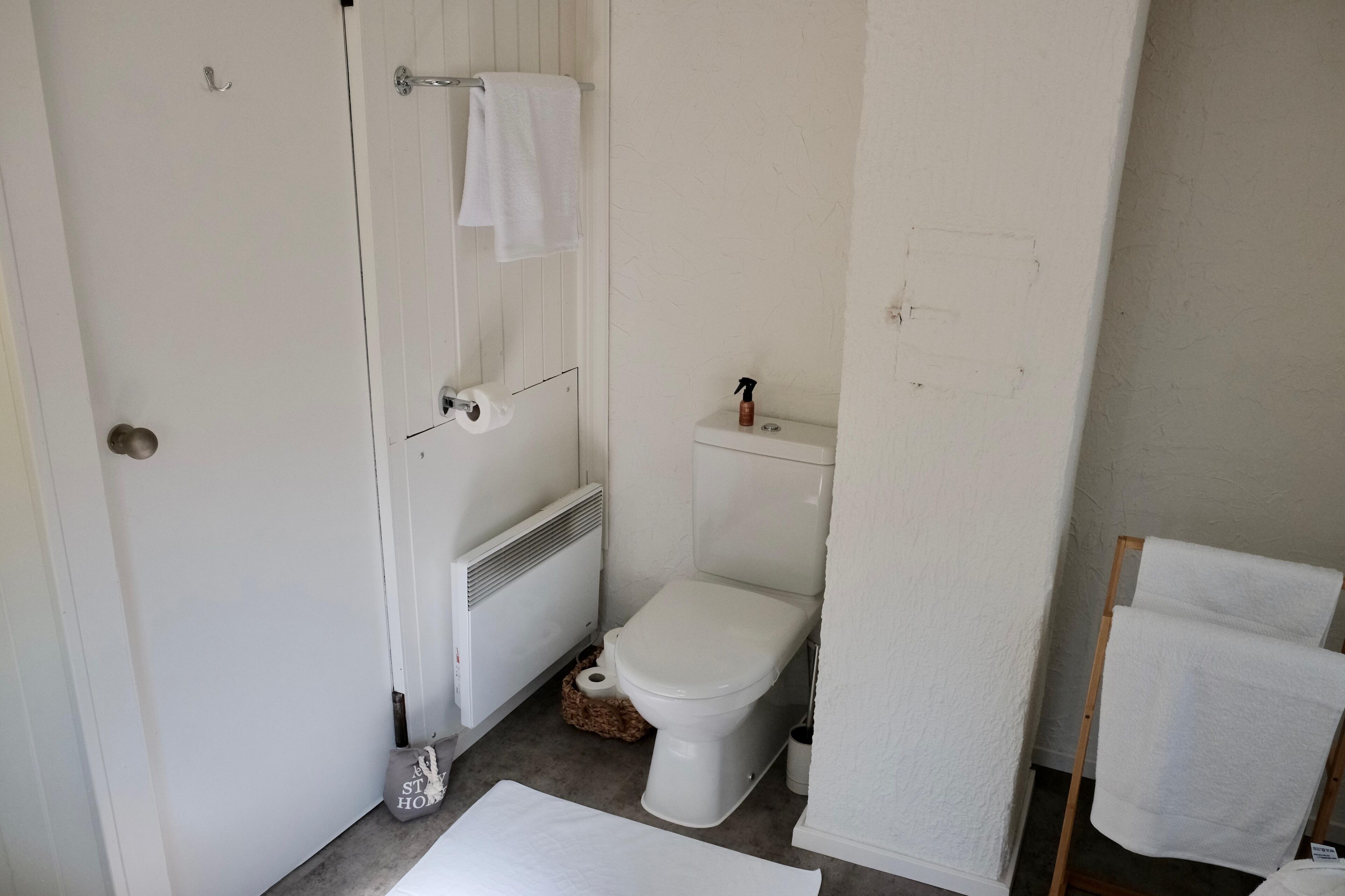 A small, clean bathroom with a toilet, a towel rack, and a radiator.