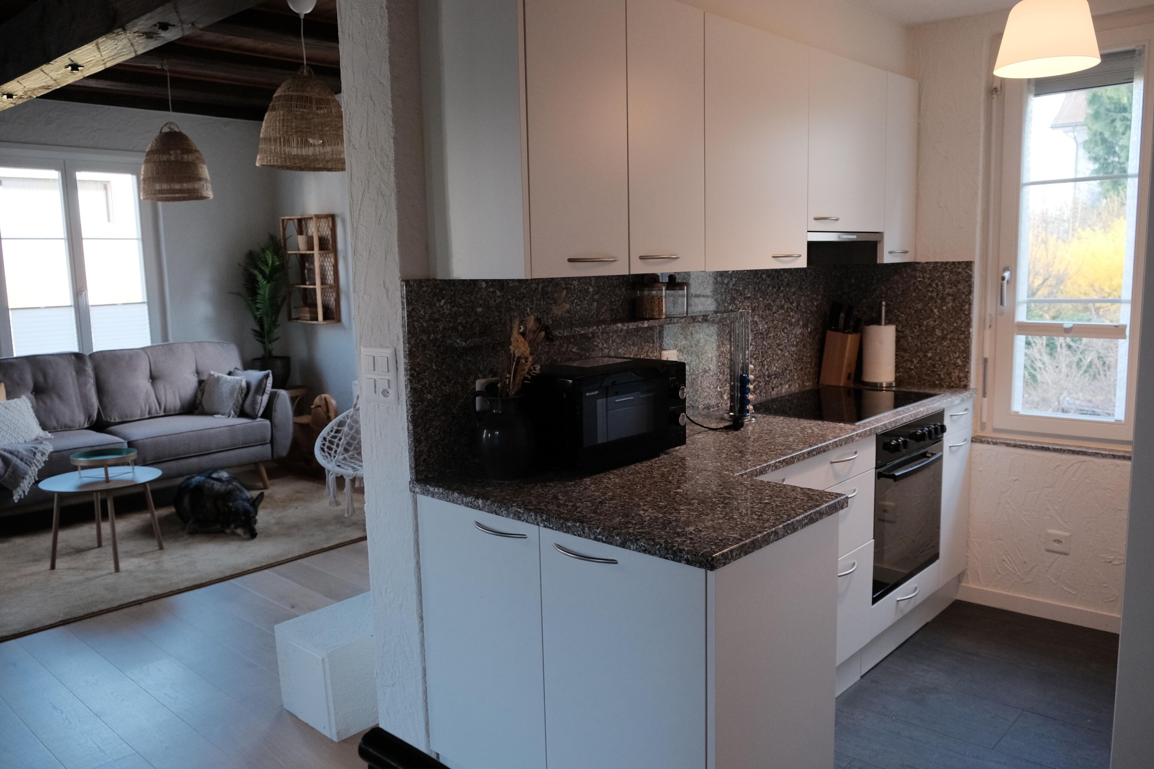 Eine moderne Küche mit weißen Schränken, Granit Arbeitsplatten, einem eingebauten Ofen und einer Mikrowelle.