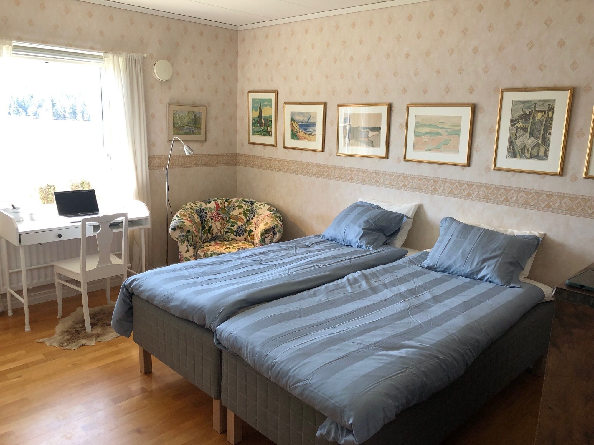 Een slaapkamer met een bed, een bureau en een stoel. Er hangen prestatiekaders aan de muur.