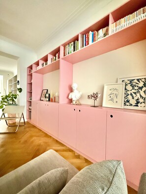 A living room with a pink bookshelf, a white bust sculpture, and framed artwork. - 2 bedrooms - baby crib & furnished  (Brussels)