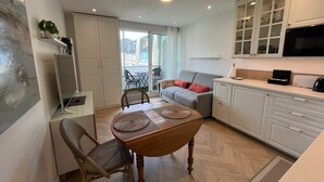 A compact living space with a dining area, kitchen, and seating area. - Studio Méva (Courseulles-sur-Mer)