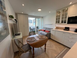 A compact living space with a dining area, kitchen, and seating area. - Studio Méva (Courseulles-sur-Mer)