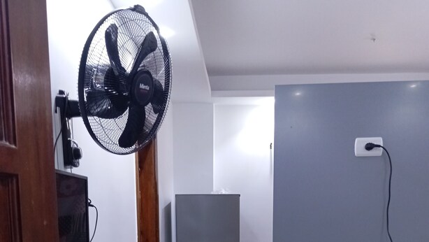 Una cocina equipada con refrigerador, microondas y ventilador.