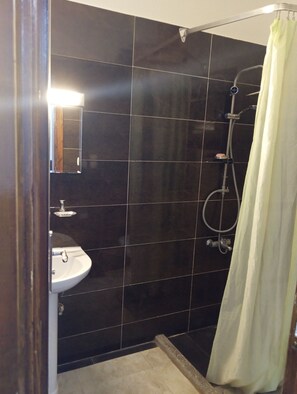 A bathroom with a sink, dark tiled walls, a shower with a curtain, and a visible faucet. - Cozy 1-bedroom studio with AC in beautiful Ourgad (ourgad)