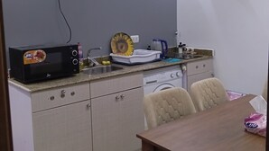 Cocina compacta con microondas, lavamanos y comedor con mesa y sillas.