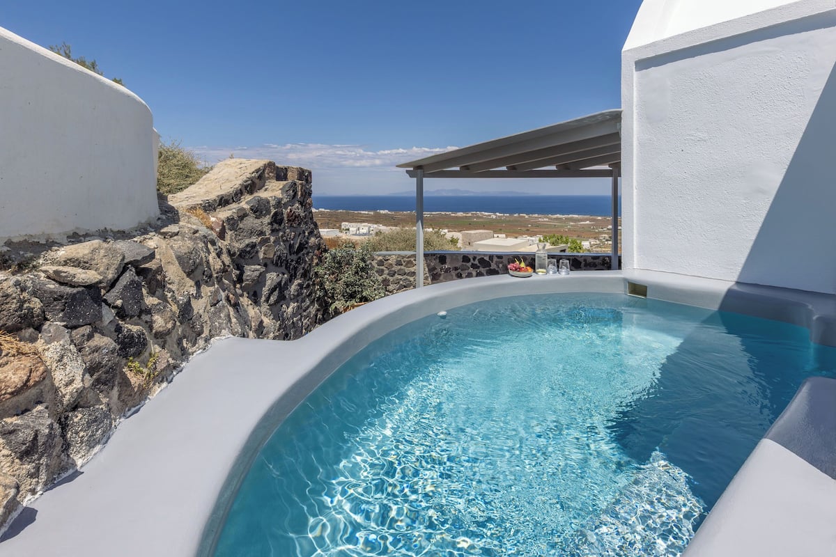 A hot tub with a view of the sea and rocky landscape.
