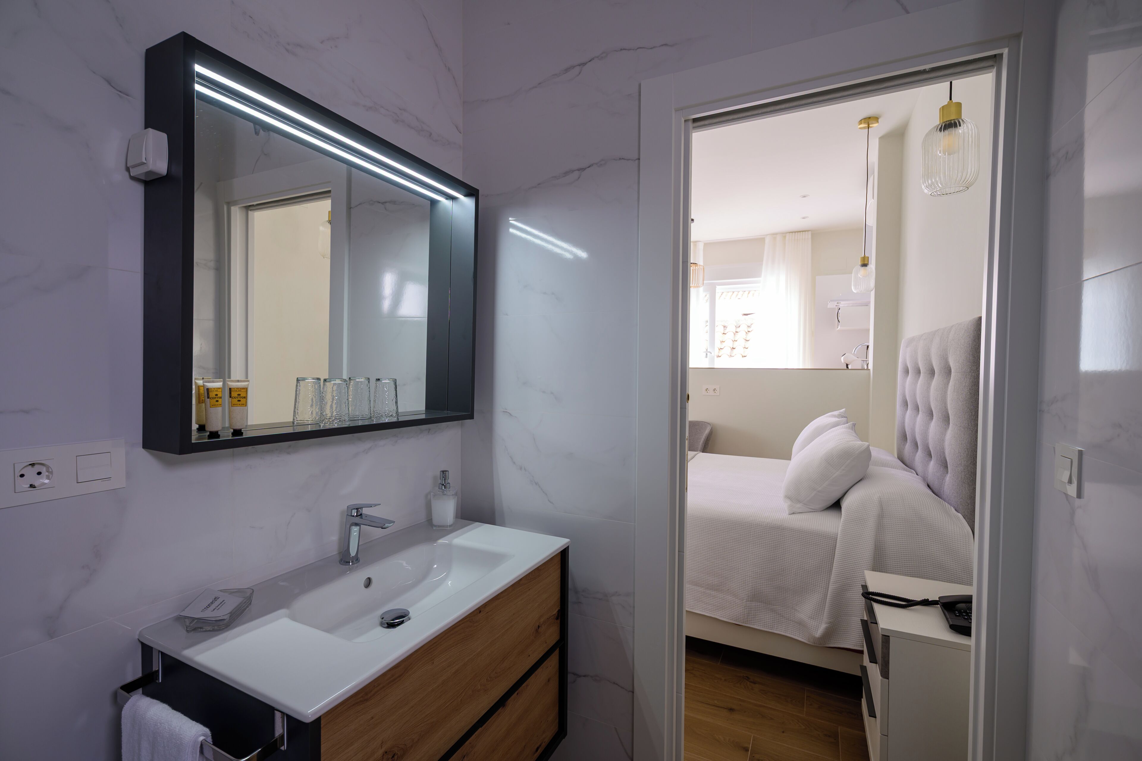 A modern bathroom with a large mirror, white sink, and wooden vanity.