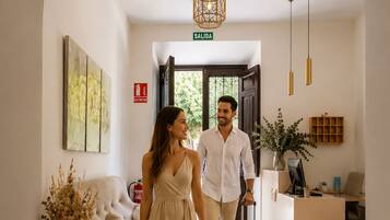 Un vestíbulo de hotel con una mesa de recepción, un cartel que indica la salida y un suelo estampado.