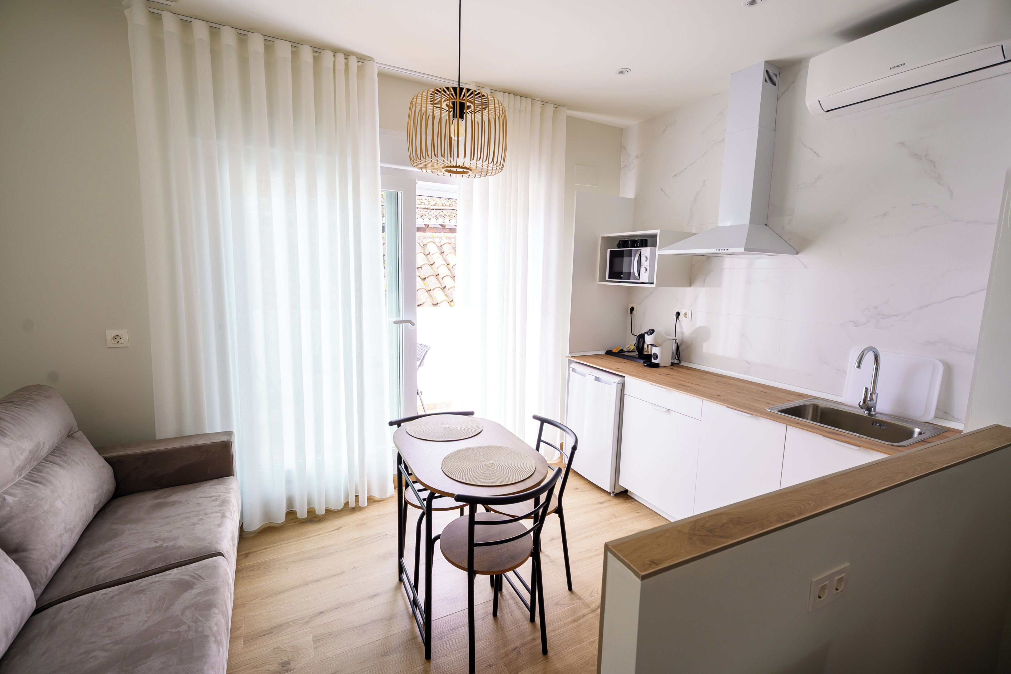 Una cocina moderna con microondas, estufa y lavaplatos. Hay un comedor con una mesa y sillas.