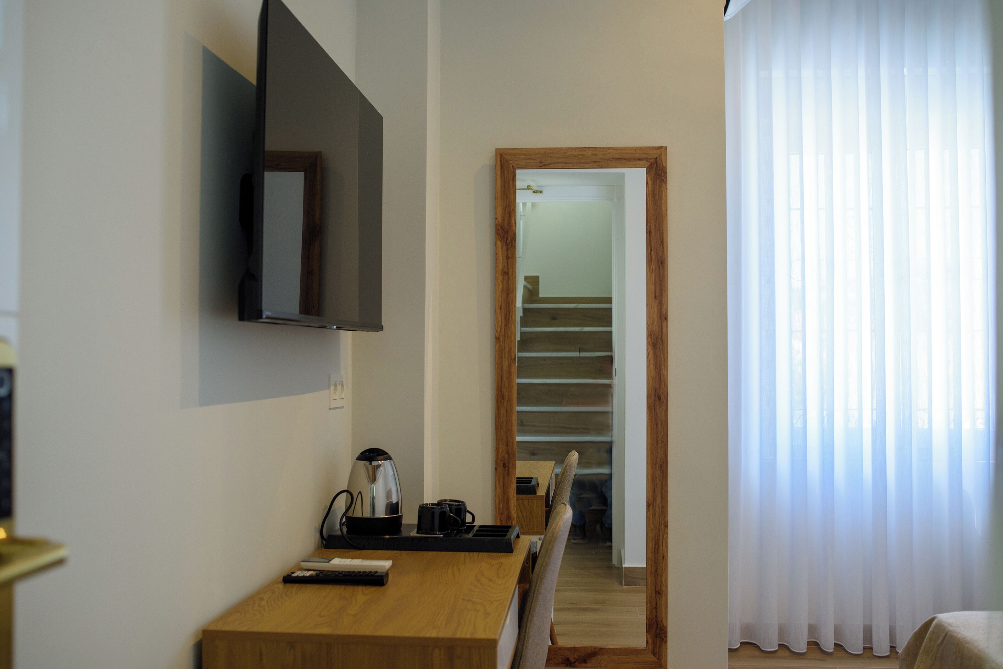 Une chambre d’hôtel avec un bureau en bois, un téléviseur fixé au mur, une machine à café et un escalier menant à l’étage supérieur.
