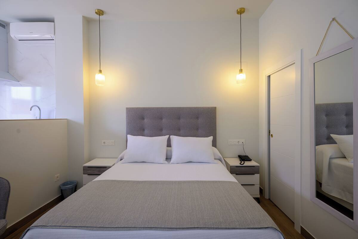 A hotel room with a large bed, two bedside tables, a mirror, and a wardrobe.