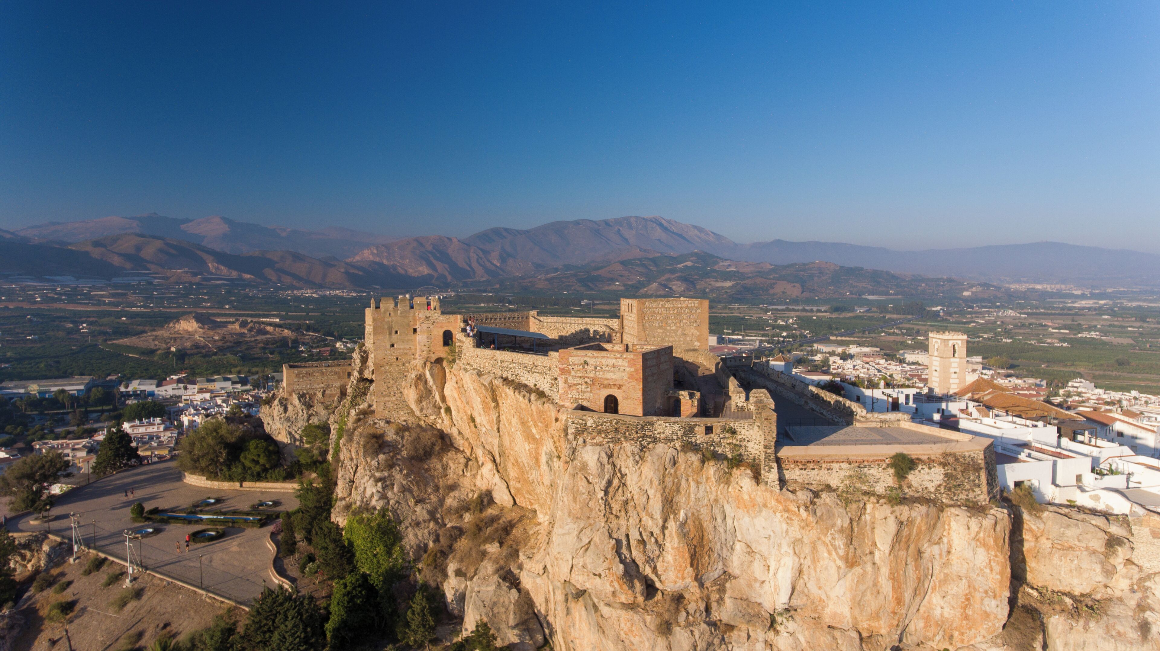 A historic stone castle atop a cliff overlooking a town.