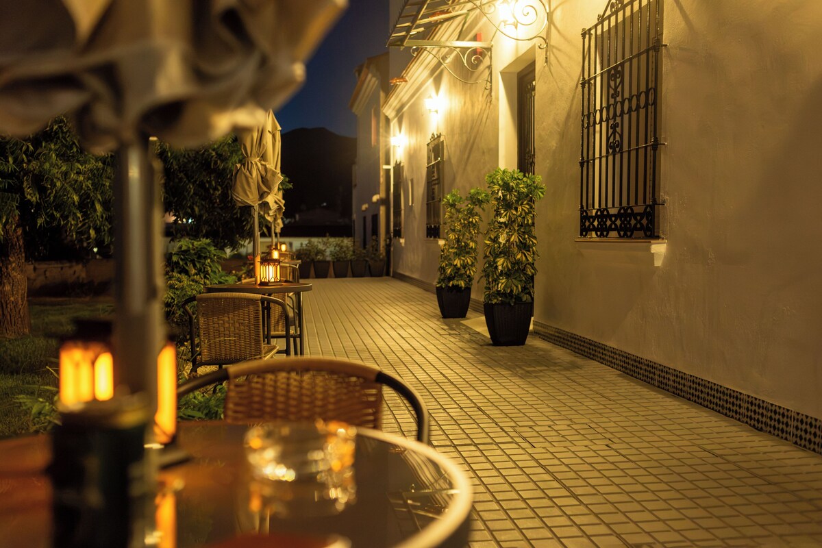 An outdoor patio area with tables and chairs, potted plants, and a tiled floor.